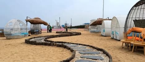 A beach with circular structures, a pathway, and a seating area.
