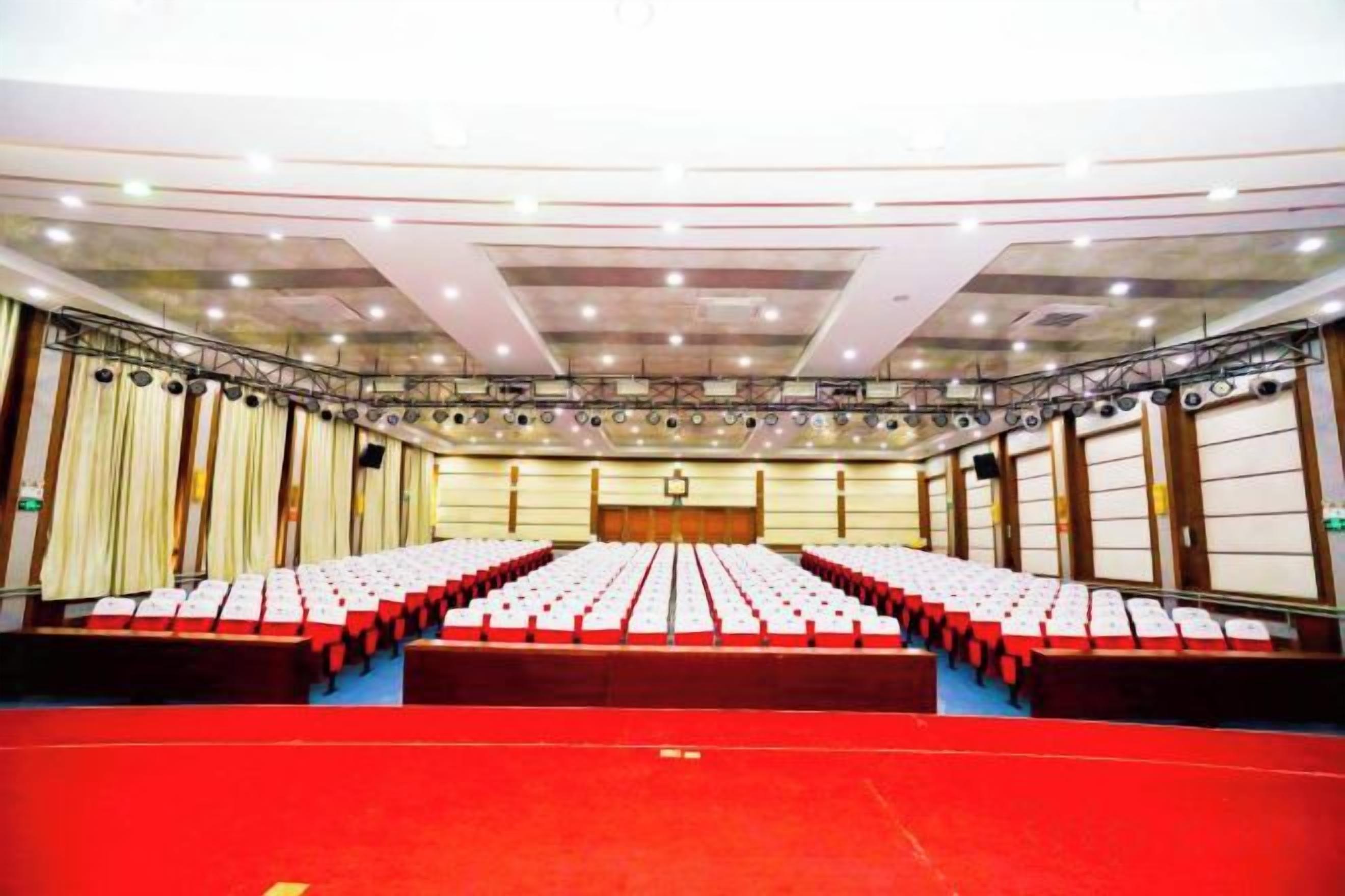 A conference room with rows of chairs, a stage, and a red carpet.