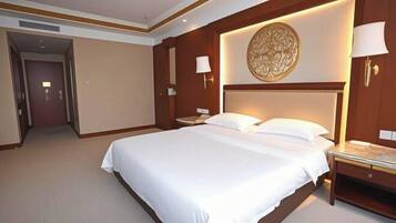 Habitación de hotel con una cama grande, una mesita de noche, una lámpara de pared y un adorno en la pared.