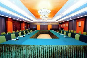 Une salle de conférence avec une longue table, des chaises et un lustre.