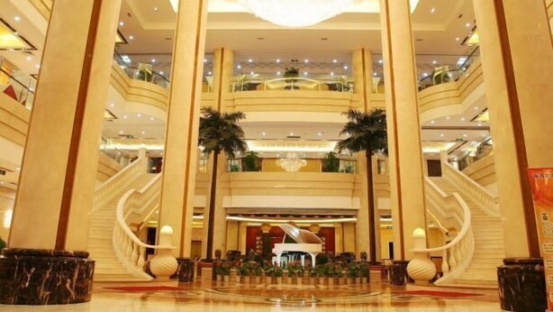 A grand lobby with multiple floors, a grand piano, and a chandelier. - Gulf Hotel (Longkou)