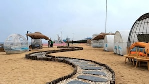 A beach with circular structures, a pathway, and a seating area. - Gulf Hotel (Longkou)