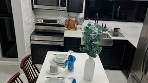 A modern kitchen with dark cabinets, stainless steel appliances, and a white countertop. - Modern Sunset Oasis - 2BD Apt w/ Pool & Views, 5 Min to Dining & Shopping (Kingston)