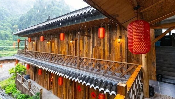 A traditional wooden building with a balcony, red lanterns, and a view of a mountainous landscape. - Changyang farming, soil and flavor farm (Changyang)