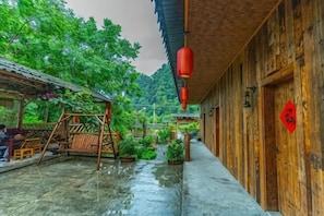 Ein Holzhaus mit überdachter Veranda, Schaukel und Blumentöpfen.