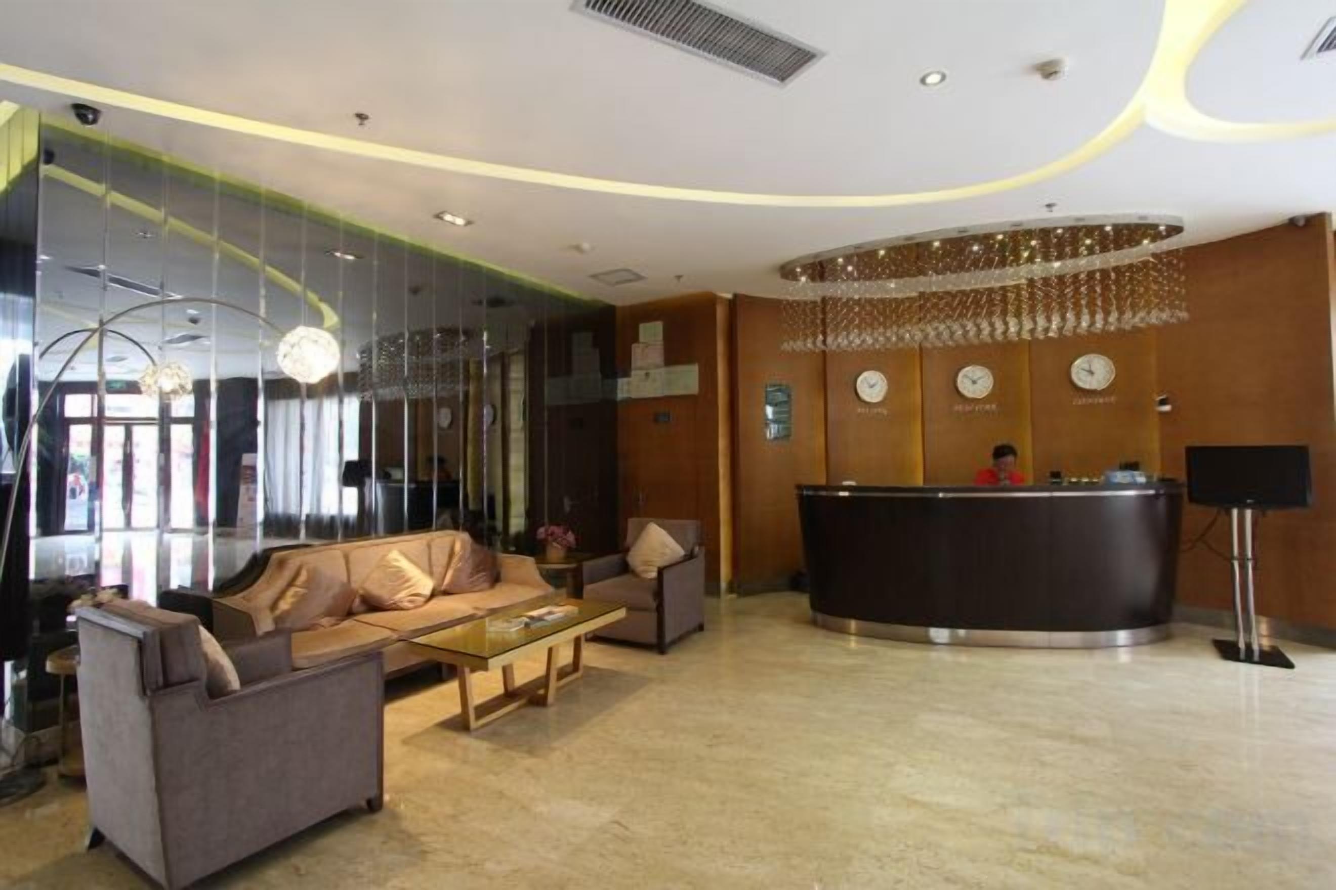 Un vestíbulo de hotel con mostrador de recepción, zona de estar y un espejo grande.