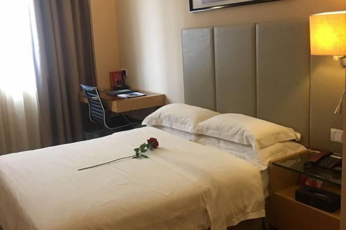 A hotel room with a bed, a bedside table, a lamp, and a chair.