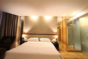 Una habitación de hotel con una cama grande, mesitas de noche con lámparas, un espejo y un armario.