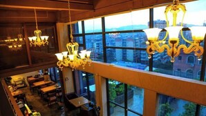 A restaurant with multiple hanging chandeliers and large windows offering a city view. - Lotus Hotel (Sihui)