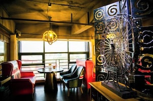Un restaurante con asientos rojos y negros, una gran rueda decorativa y vistas a través de amplios ventanales.