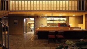 A bar area with a wooden counter, bar stools, and a wine rack. - Lotus Hotel (Sihui)