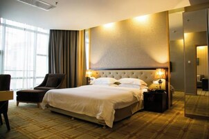 Una habitación de hotel con una cama grande, una silla, un escritorio y un espejo.