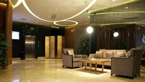 A lobby with a reception desk, seating area, and a large plant. - Lotus Hotel (Sihui)