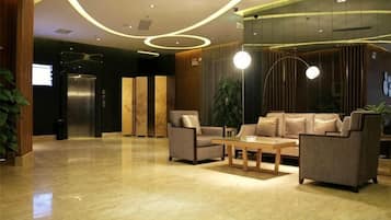 A lobby with a reception desk, seating area, and a large plant.