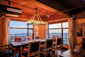 A dining area with a table and chairs, large windows, and a hanging light fixture. - Lotus Hotel (Sihui)