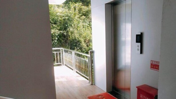 A hallway with a wooden floor, a red mat, and a red box on the right. - Jianshi Hongshan Villa (Jianshi)
