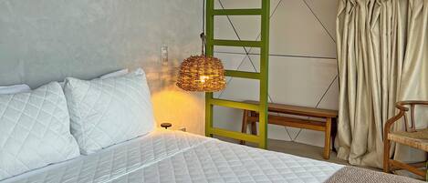 Un dormitorio con una cama, una lámpara colgante, un banco y una escalera.