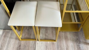 Une table à manger avec deux chaises blanches, un chemin de table à motifs et un mur décoratif.