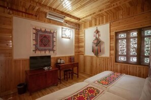 A wooden-paneled room with a bed, a desk, a television, and wall decorations. - Puzhehei Ancient Courtyard (Qiubei)