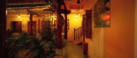 A corridor with a wooden ceiling, potted plants, and a staircase.