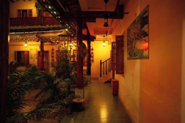 A corridor with a wooden ceiling, potted plants, and a staircase. - Puzhehei Ancient Courtyard (Qiubei)