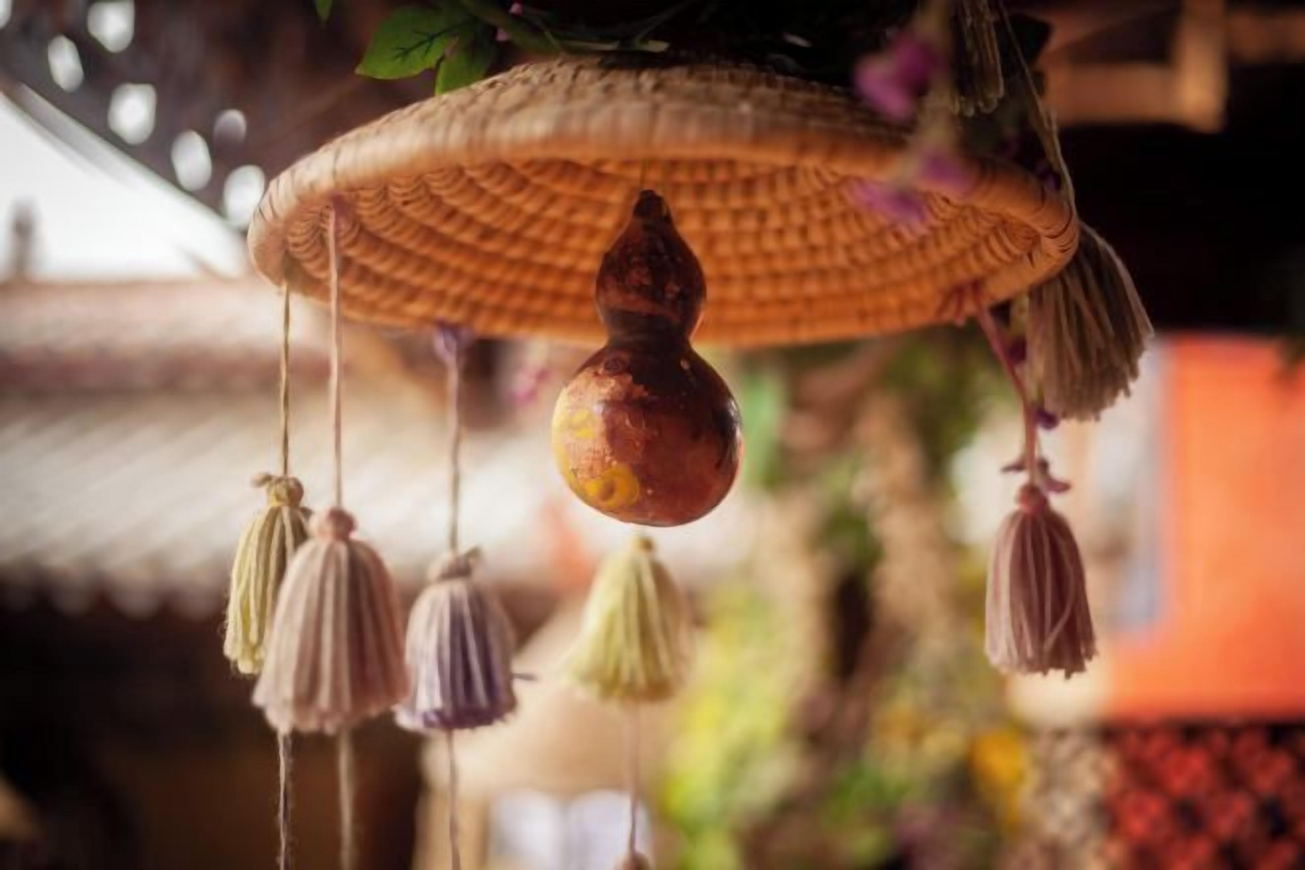 Un objet décoratif suspendu, composé d’un panier tressé et de quelques glands.