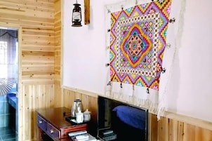Um quarto com painéis de madeira, lareira, televisão e uma tapeçaria colorida na parede.