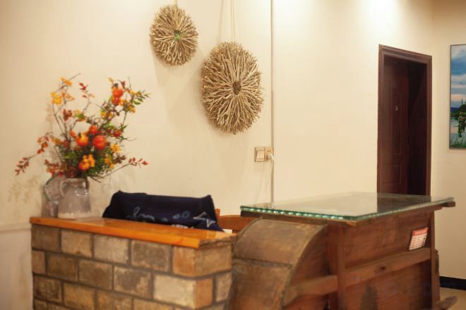 Un mostrador de recepción con un florero, un banco de madera y dos adornos en la pared.