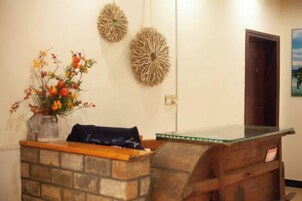 A reception desk with a vase of flowers, a wooden bench, and two wall decorations.