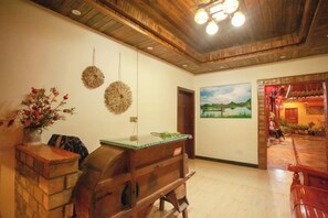 A room with a wooden ceiling, a painting on the wall, and a wooden bench. - Puzhehei Ancient Courtyard (Qiubei)