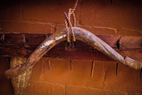 Una estructura de madera rústica con una viga curvada y una cuerda atada a ella, frente a un muro de ladrillo.