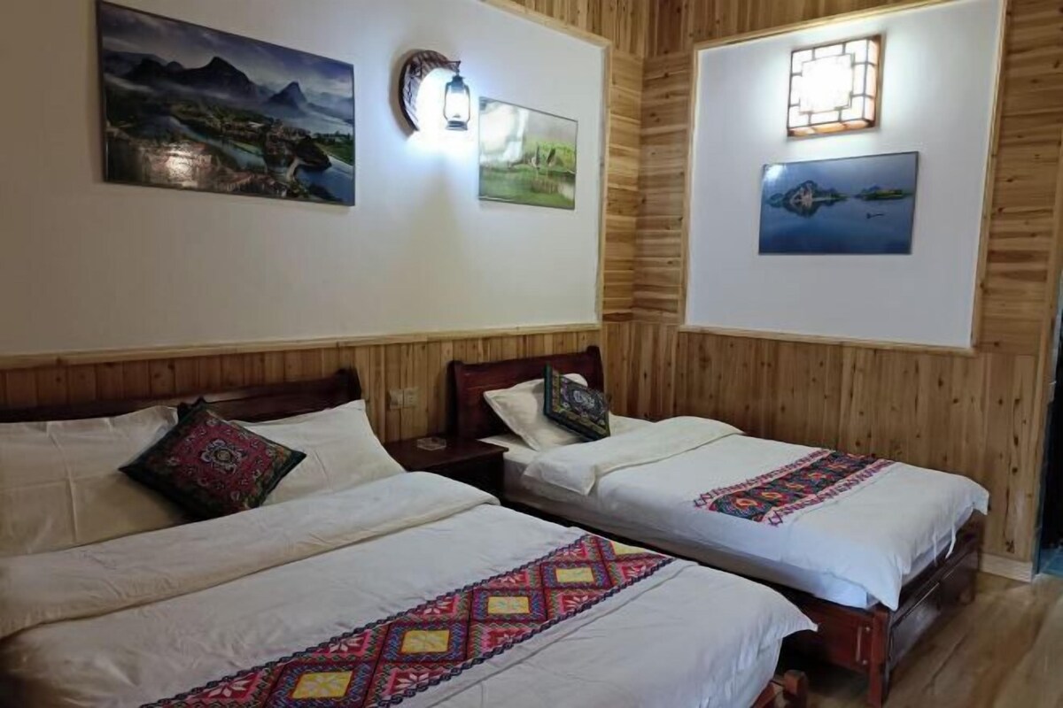 Two single beds with wooden headboards, white linens, and colorful embroidered bedspreads.