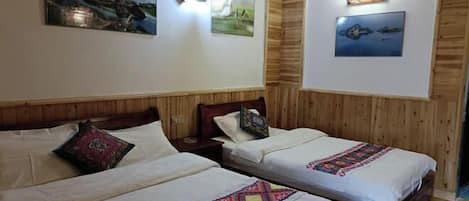 Two single beds with wooden headboards, white linens, and colorful embroidered bedspreads.