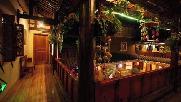 Un intérieur traditionnel en bois, comprenant un comptoir d’accueil, un plancher en bois et une composition décorative de plantes suspendues.