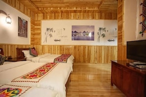 A room with wooden panel walls, a bed with a colorful bedspread, a TV, and artwork on the wall.