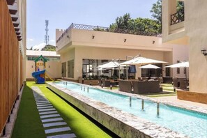 Relax by the pool surrounded by lush greenery and lounge under the shade of umbrellas.