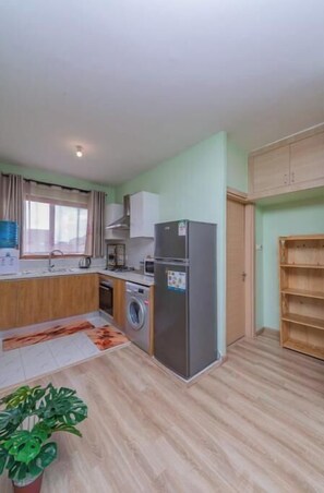 Compact kitchen with a washing machine, microwave, and refrigerator, offering a convenient space for meal preparation.