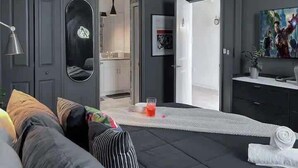 Um quarto moderno com uma cama, um espelho, uma televisão e uma porta que dá para um banheiro.