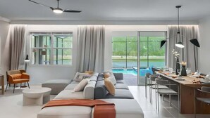 Sala moderna com um sofá grande, uma mesa de jantar e vista para uma piscina.