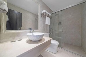 A modern bathroom with a large mirror, a marble sink, a toilet, and a glass-enclosed shower. - Longhao Hotel (Wenzhou)