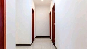 A corridor with doors on both sides, a tiled floor, and a ceiling light. - Huashu Inn (Huayin)