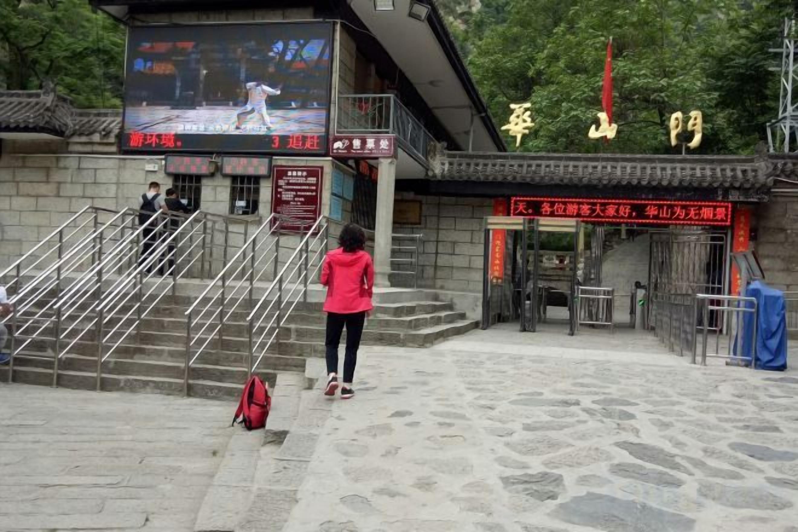 A stone staircase leading to a building with a large screen displaying a sports event.