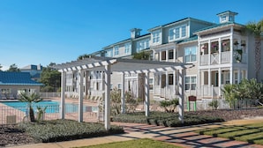 A two-story building with a covered outdoor seating area and a swimming pool. - The Village at Blue Mountain Beach (Santa Rosa Beach)