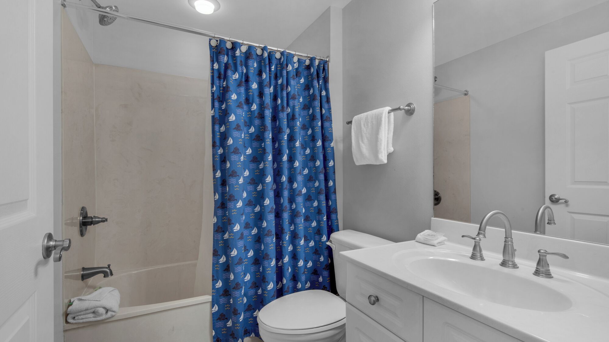 A bathroom with a shower, toilet, sink, and a mirror.