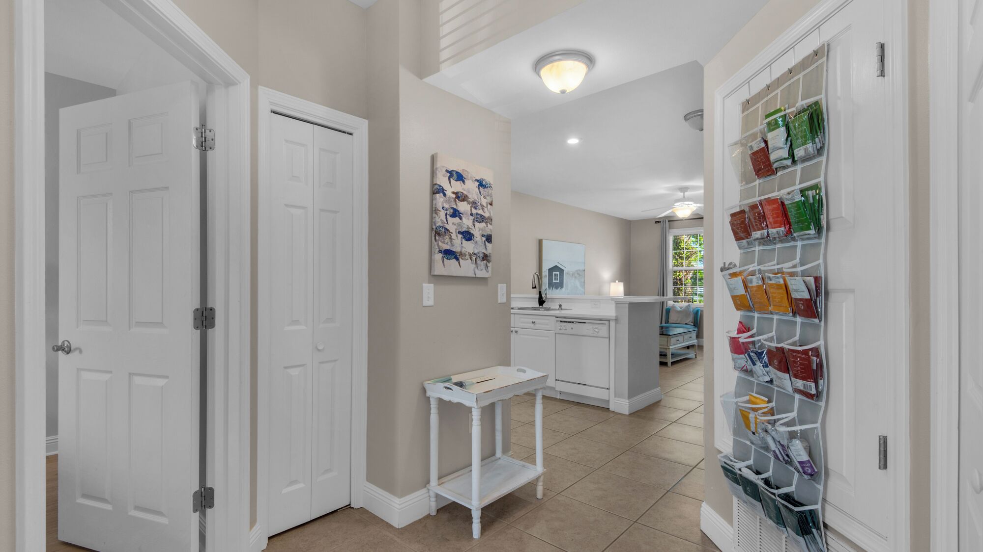 A hallway with white doors, a kitchen area with a sink and cabinets, and a storage unit with bags.