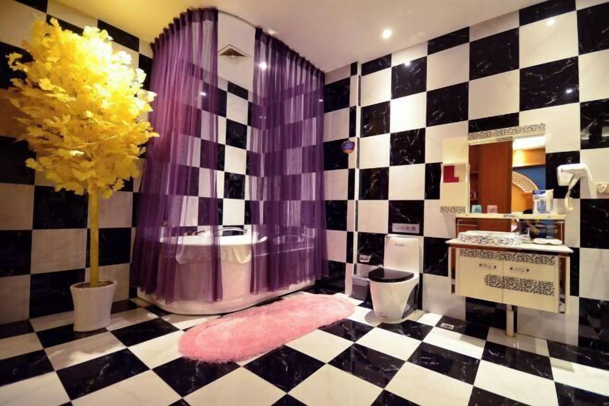 A bathroom with a checkered floor, a sink, a toilet, and a decorative tree.