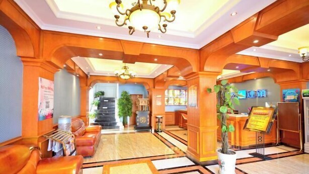 A lobby with wooden paneling, a reception desk, a chandelier, and a reception area with a plant. - Guoran Theme Hotel (Wuhan Huquan) (Wuhan)