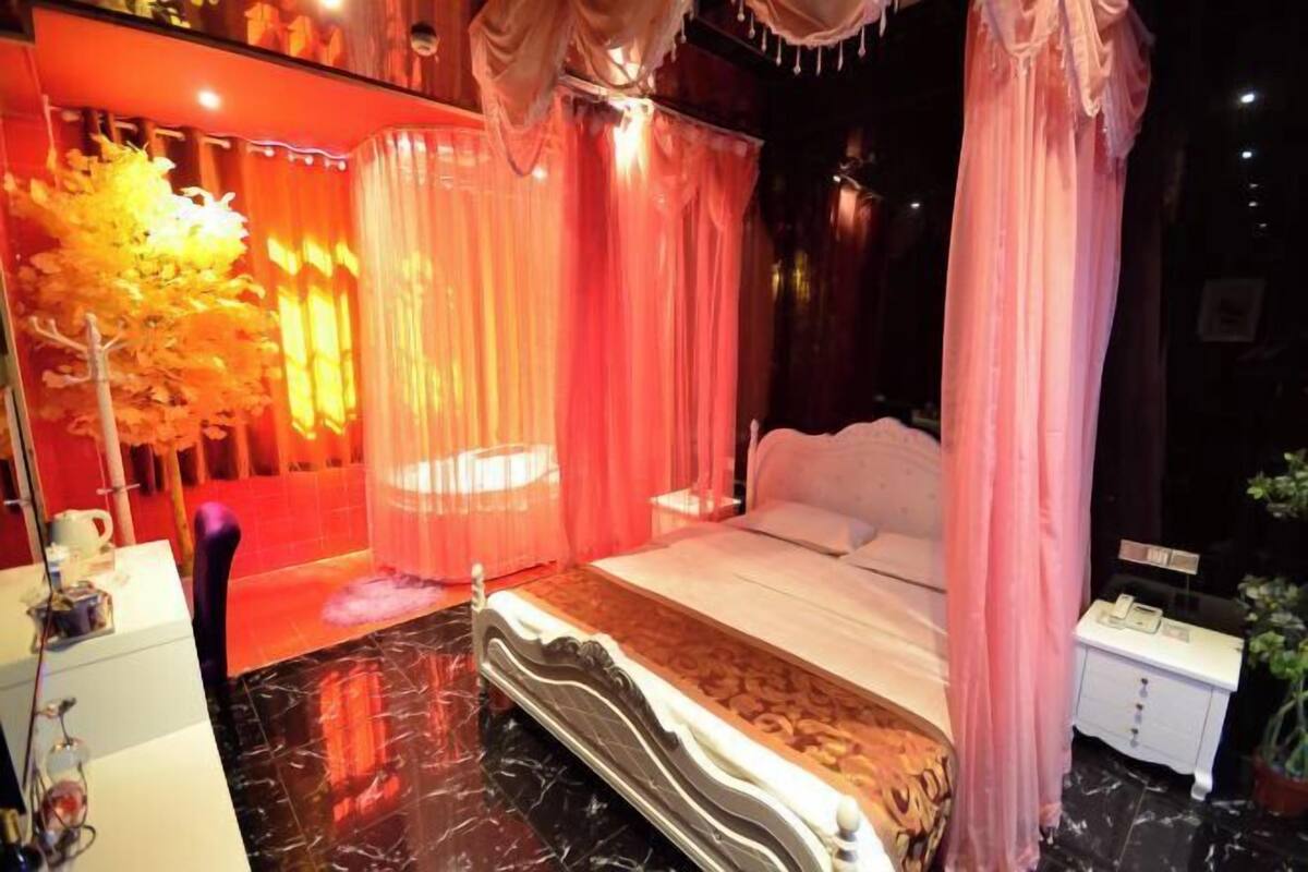 A bedroom with a bed, curtains, a nightstand, and a small table.