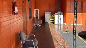 Un pasillo con extintor, una silla, una mesita, un refrigerador y un armario amarillo.