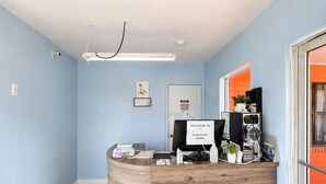 Un mostrador de recepción con una computadora, un cartel que indica tarifas por mascotas y una puerta con un letrero de oficina.